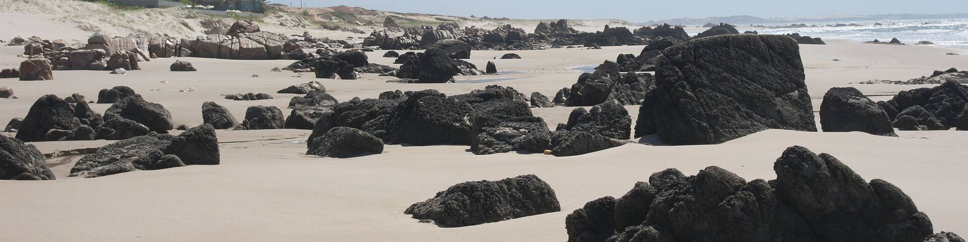A rocky beach with large boulders and a clear sky.
