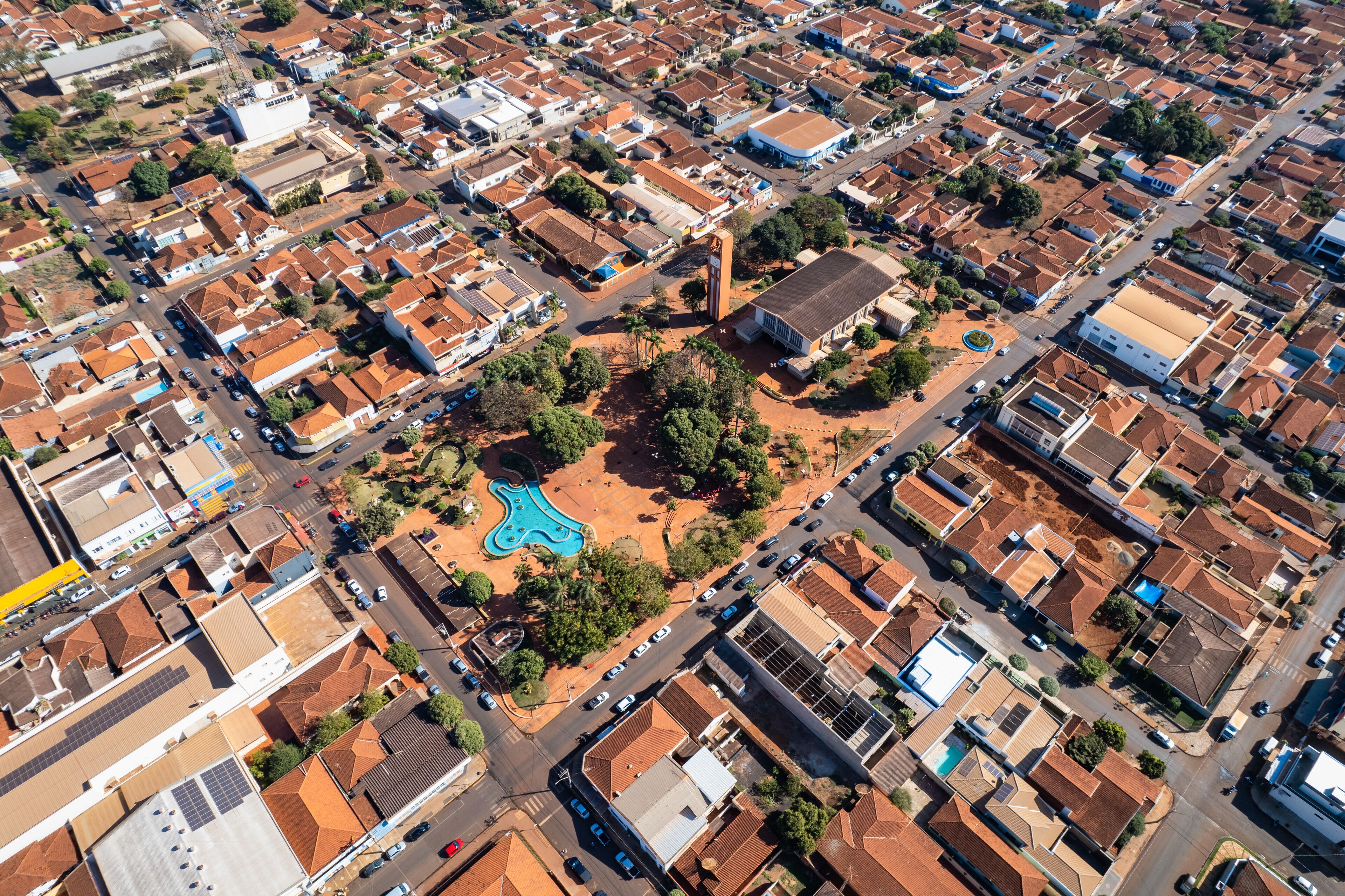 An aerial view of a residential area with a central park, a prominent blue building, and a large white structure.