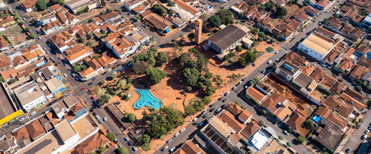 An aerial view of a residential area with a central park, a prominent blue building, and a large white structure.
