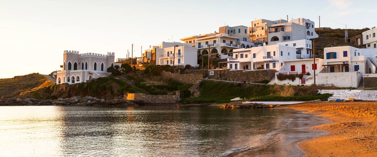 A coastal town with white buildings, a castle-like structure, and a beach.