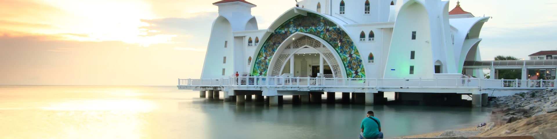 Man looking at the Majestic view of Malacca Straits Mosque during sunset.