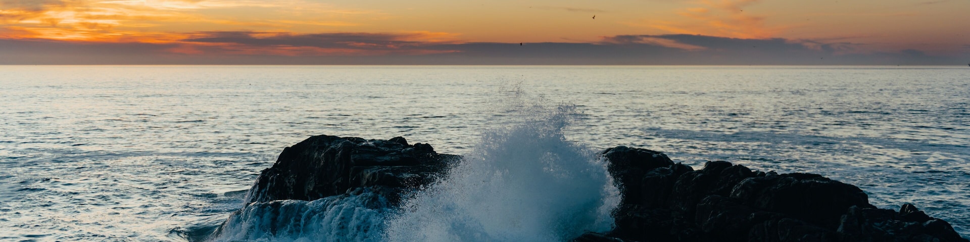 Waves of the Atlantic Ocean during sunset, beautiful strong waves with splashes near rocky beach, banner size
