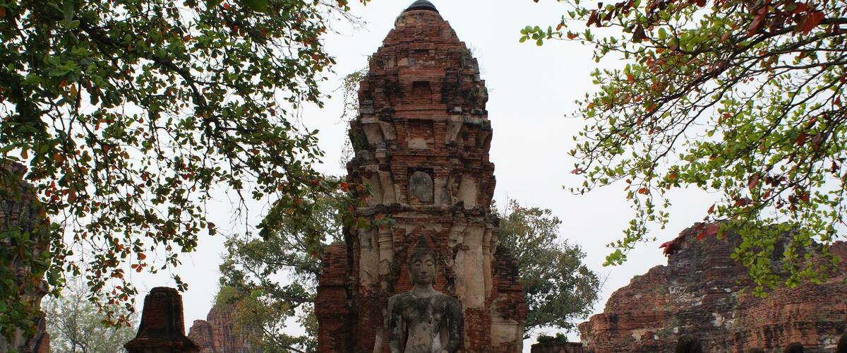 An ancient temple with a central statue surrounded by smaller statues and brick structures.
