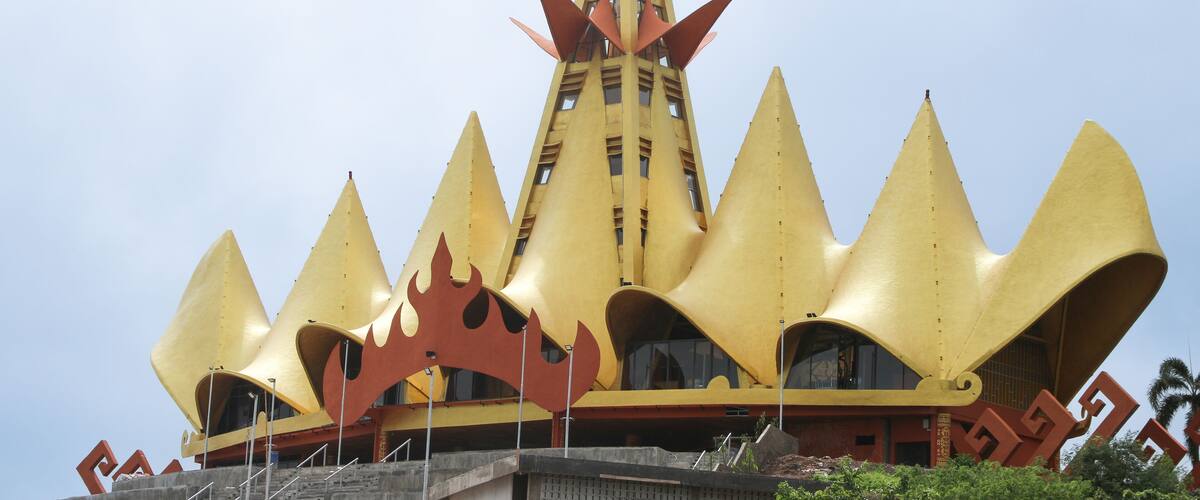 A yellow building with a unique, pointed roof design and a central tower.