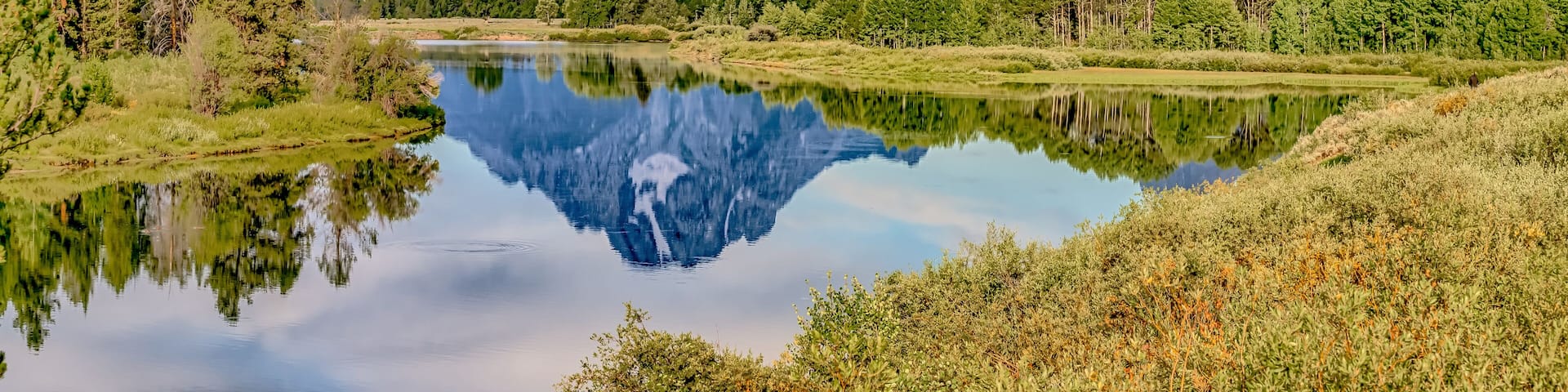A mountain range, a calm lake, and a forested area.