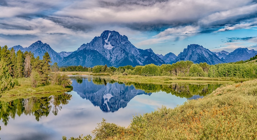 A mountain range, a calm lake, and a forested area.