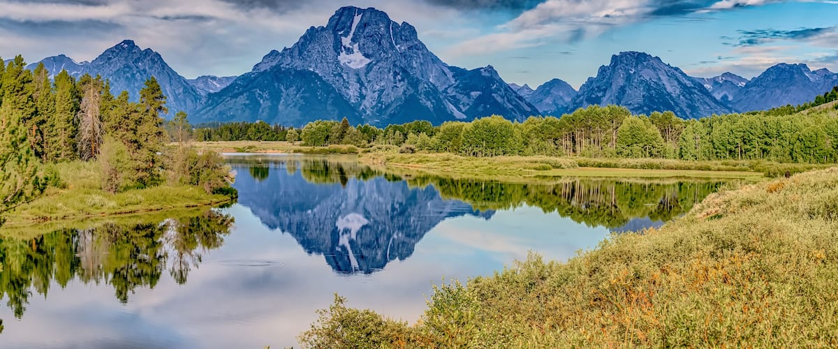 A mountain range, a calm lake, and a forested area.