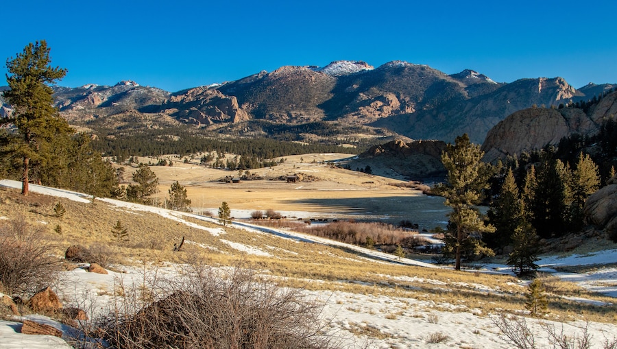 Un paysage montagneux comprenant une vallée, un sol recouvert de neige et une végétation clairsemée.