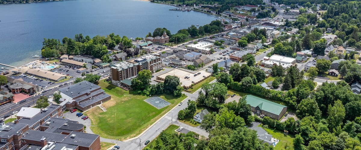 A lakeside town with a prominent church, a sports field, and surrounding greenery.