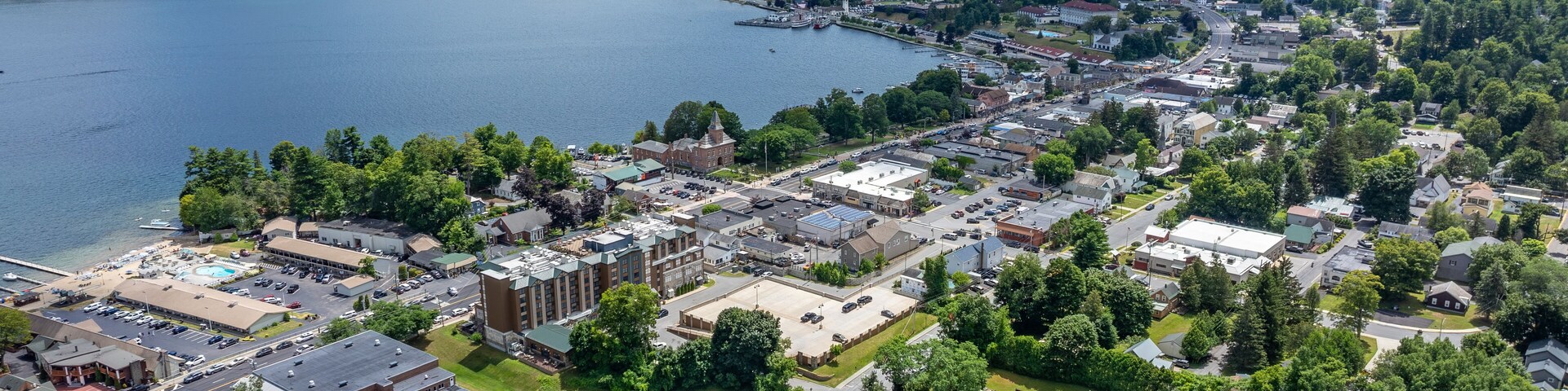 A lakeside town with a prominent church, a sports field, and surrounding greenery.