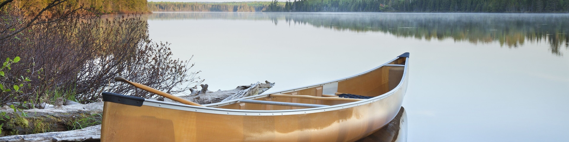 Yellow canoe on shore of northern Minnesota lake in early morning light