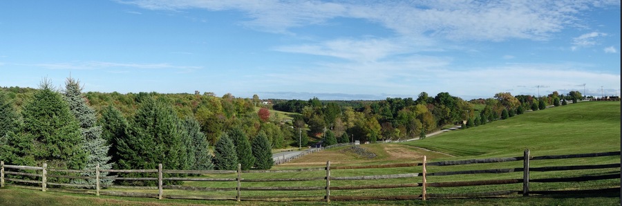 A sweeping view of what was once Max Yasgur's dairy farm in Bethel, New York; the site of the original Woodstock Music Festival held in 1969. There is a peace sign at the right mowed into the grass.