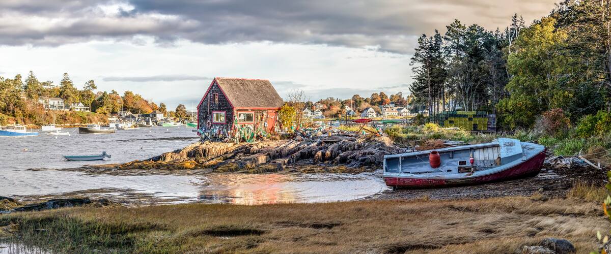 A coastal scene with a house, boats, and a rocky shoreline.
