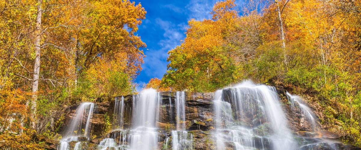Una cascata a più livelli circondata da alberi dai colori autunnali.