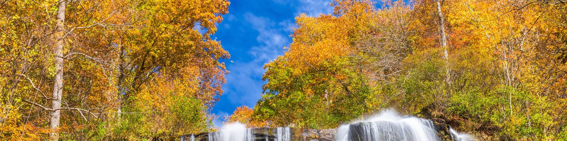 A multi-tiered waterfall surrounded by autumn-colored trees.