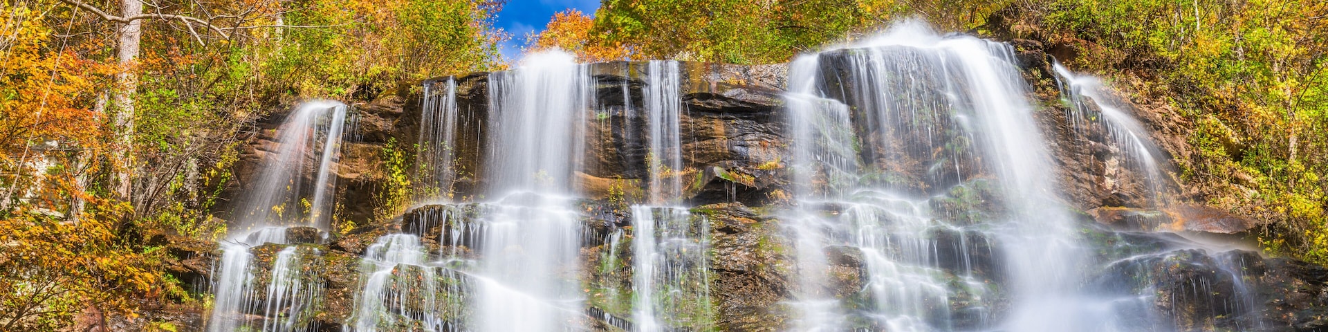 A multi-tiered waterfall surrounded by autumn-colored trees.