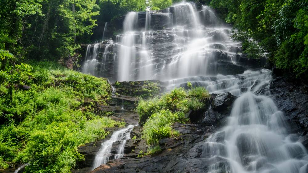 A multi-tiered waterfall surrounded by lush greenery.
