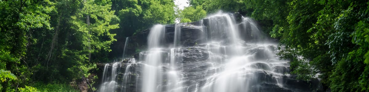A multi-tiered waterfall surrounded by lush greenery.