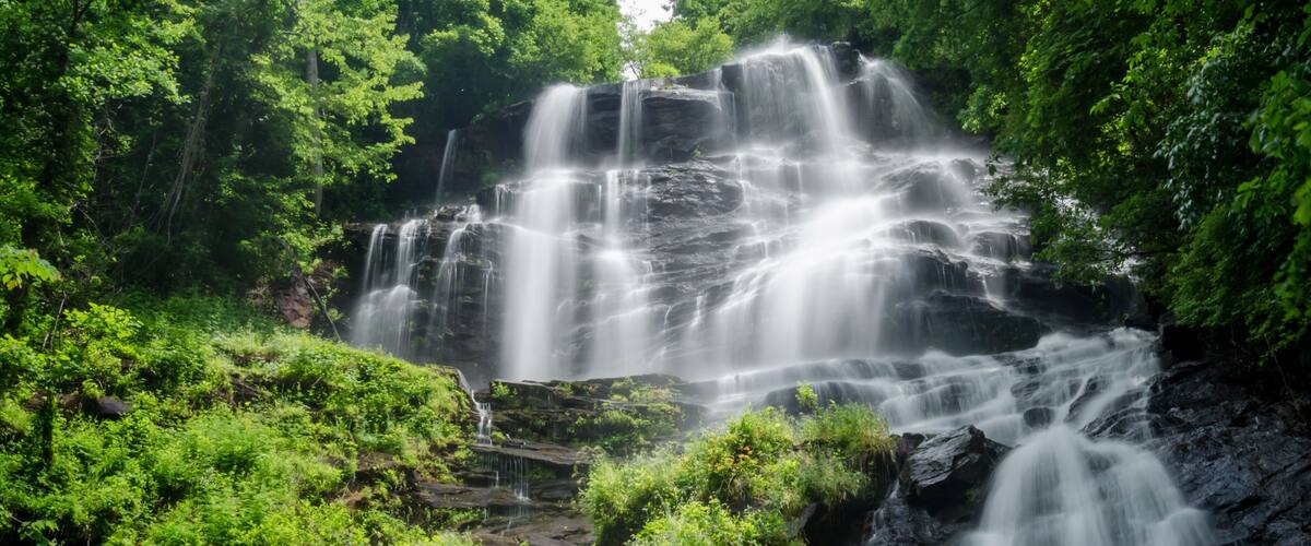 A multi-tiered waterfall surrounded by lush greenery.