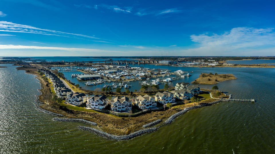A marina with boats, a bridge, and houses along the water's edge.