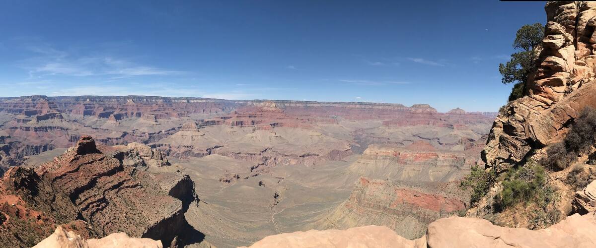 A vast canyon with layered rock formations and a clear blue sky.