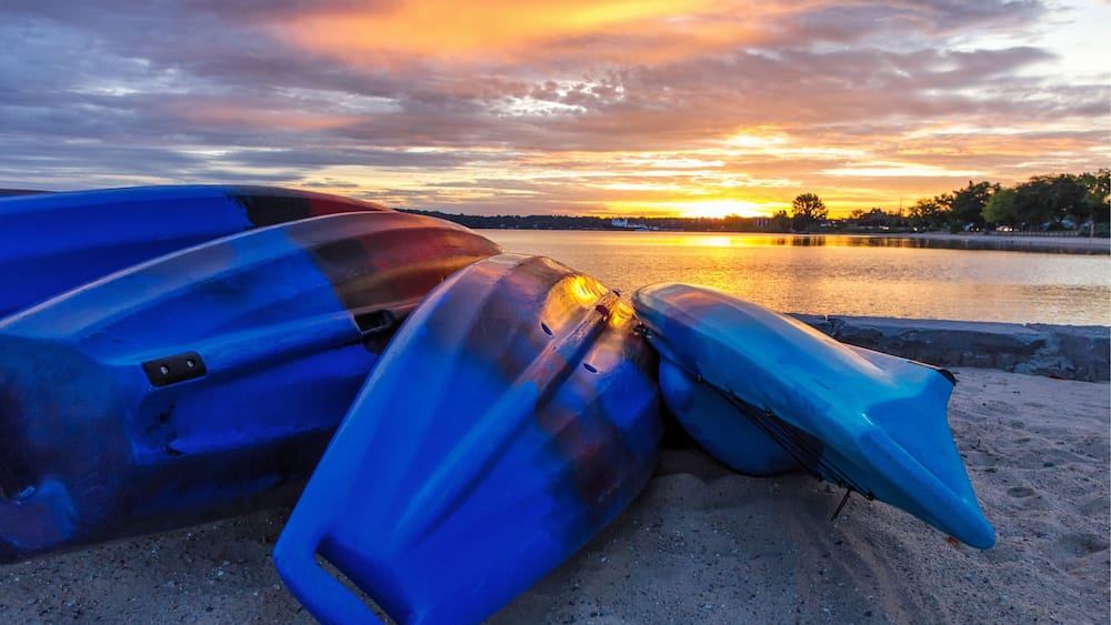 Summer Lake Sunrise Background. Kayaks line the lakeshore with vibrant and beautiful sunrise colors in the background. Grand Traverse Bay in Traverse City, Michigan, USA.