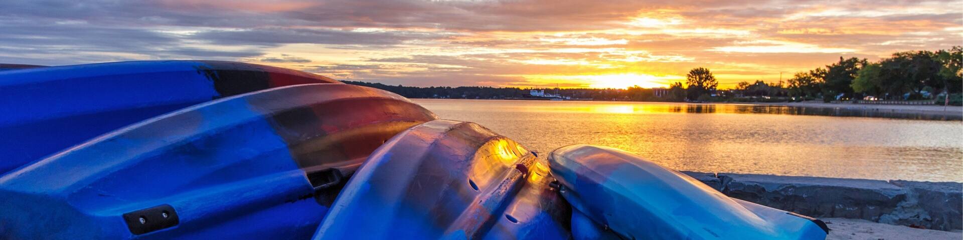 Summer Lake Sunrise Background. Kayaks line the lakeshore with vibrant and beautiful sunrise colors in the background. Grand Traverse Bay in Traverse City, Michigan, USA.