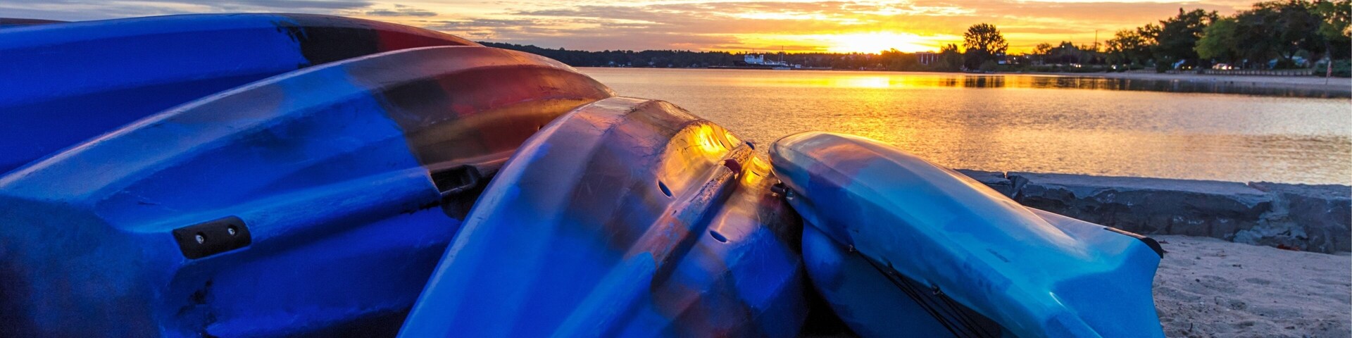 Summer Lake Sunrise Background. Kayaks line the lakeshore with vibrant and beautiful sunrise colors in the background. Grand Traverse Bay in Traverse City, Michigan, USA.