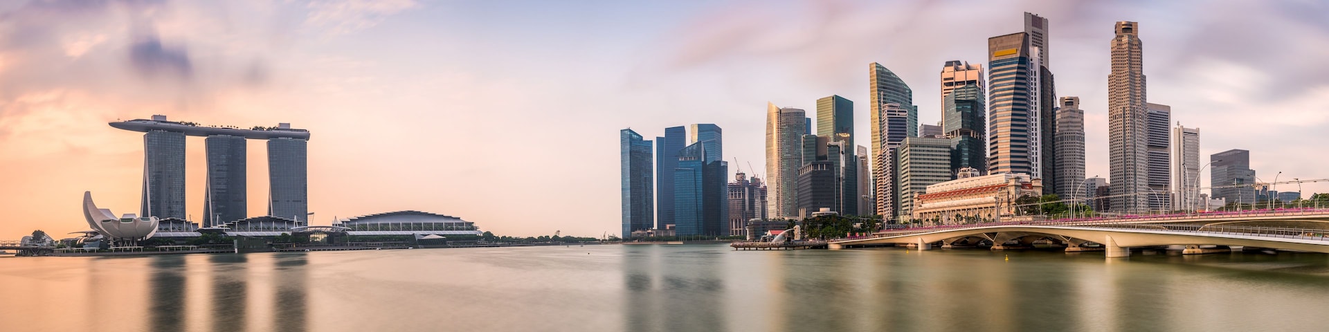 Une vue panoramique d’une ville, avec ses gratte-ciel modernes, un pont et une étendue d’eau dans laquelle se reflètent les bâtiments.