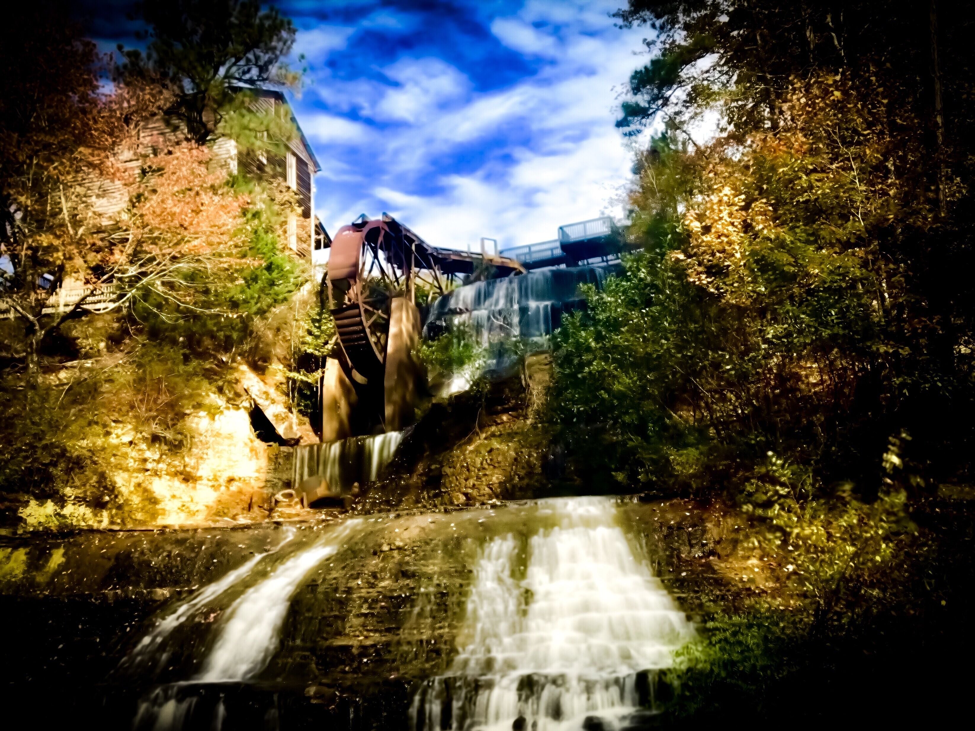 A waterfall cascading over a bridge surrounded by trees.