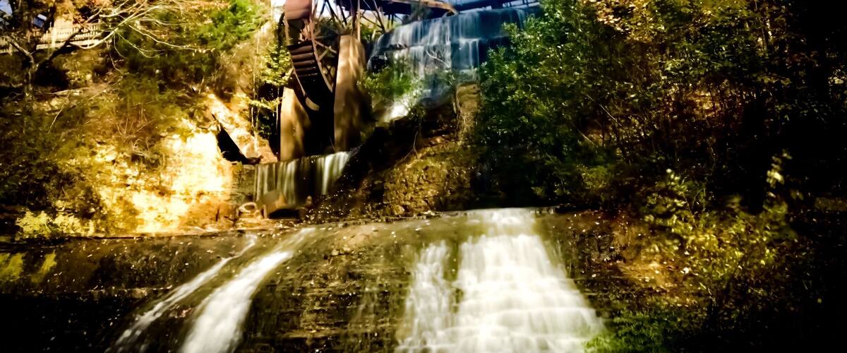 A waterfall cascading over a bridge surrounded by trees.