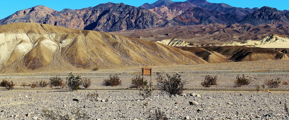 A rocky desert landscape with mountains in the background.