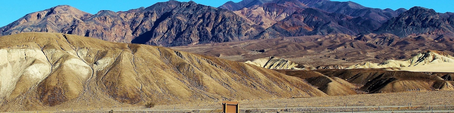 A rocky desert landscape with mountains in the background.