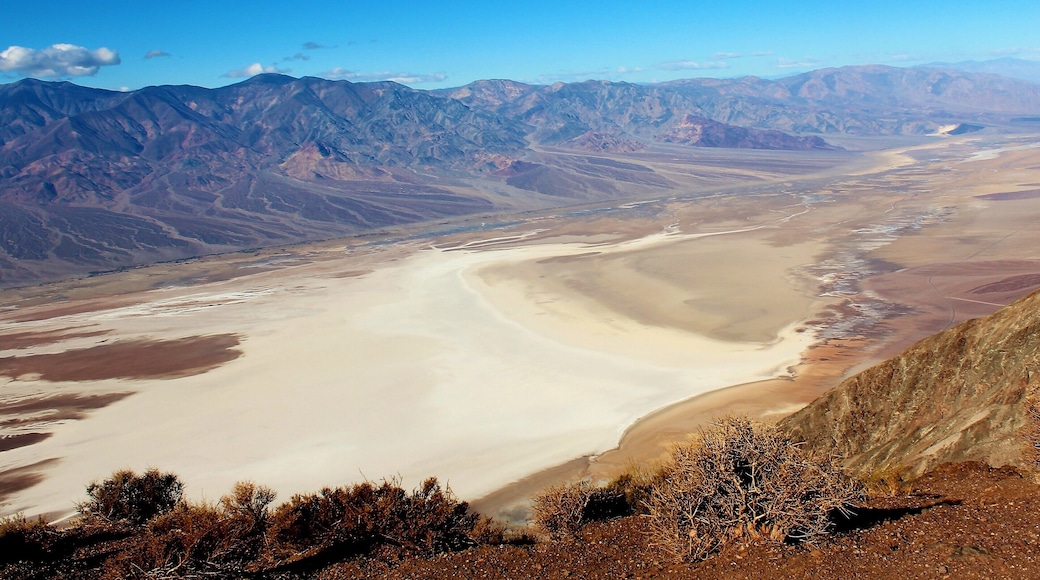I took this photo at Death Valley National Park, in California USA. From Dante's View! One of the best viewpoints in this otherworldly national park. I had a memorable time there in December 2016. My 1st time ever in California. But it was only for 1 day, as I was based in Las Vegas. But Death Valley National Park was somewhere I've wanted to go for a very long time. I love this kind of foreboding and otherworldly landscape! And more about this photo and Dante's View: It's a viewpoint terrace at 1,669 m (5,476 ft) height, on the north side of Coffin Peak, along the crest of the Black Mountains, overlooking Death Valley. All quite dark and macabre names, if I do say so myself! Dante's View was even used as a filming location in the 1st Star Wars film. And that big white spot in this photo is a huge salt flat at Badwater Basin. Badwater Basin is the the lowest point in North America, at 282 ft (86 m) below sea level. And Death Valley itself is notoriously hot in many months of the year. It's one of the hottest places in the world in the summertime. I'm glad I went in a December ;). But from this viewpoint it was so cold from the chilly temperature and strong wind that I was forced to quickly put on gloves and a hat ;). All part of the incredible experience!