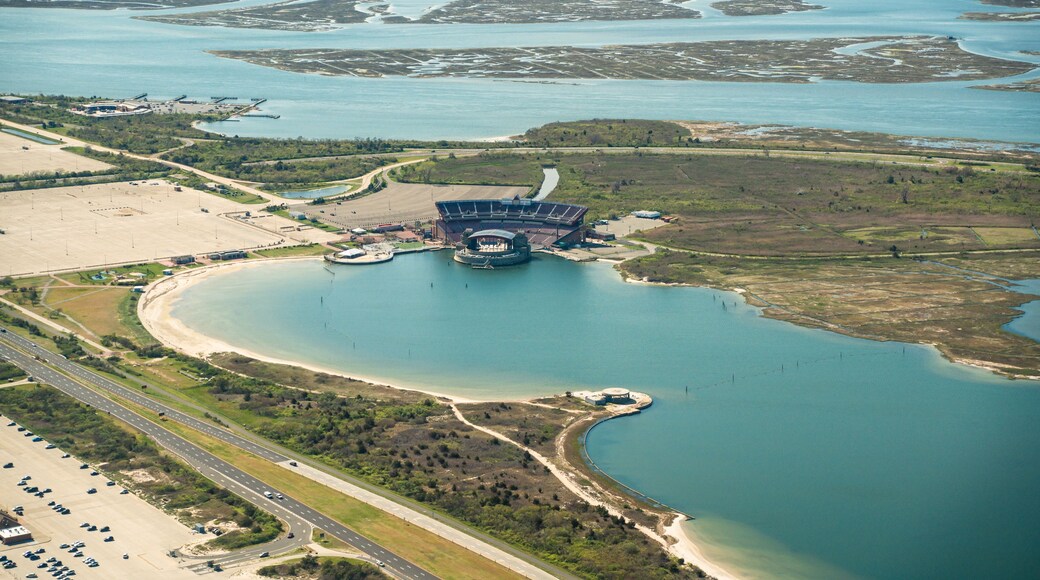 An aerial view of a coastal area with a large stadium, a marina, and a highway.