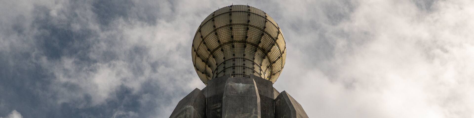 A tall, cylindrical structure with a spherical top and a grid-like pattern on the upper part.