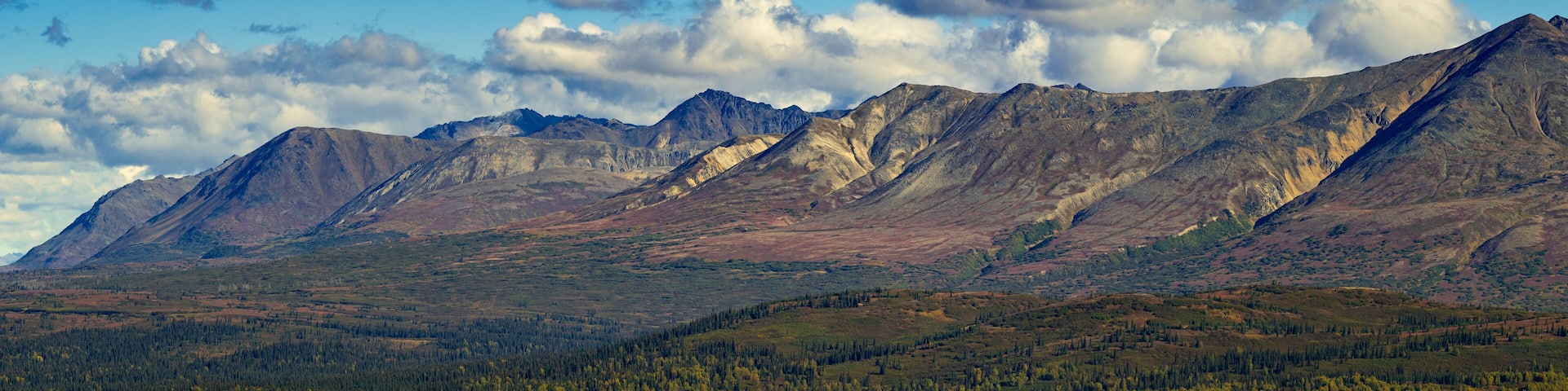 A mountain range with a clear sky and scattered clouds.