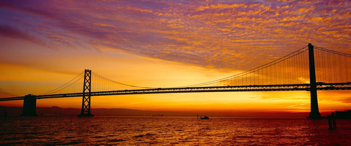 A suspension bridge at sunset with a vibrant sky.
