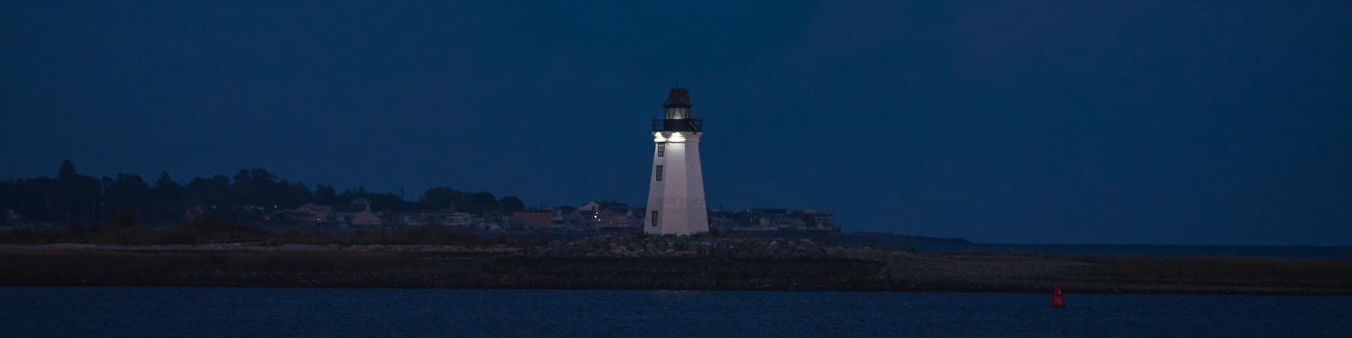 A full Hunter Moon rises over the Fayerweather Lighthouse in Bridgeport Harbor, Long Island Sound, Connecticut.