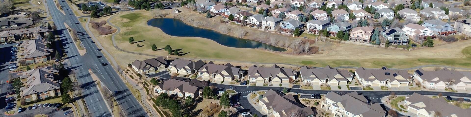 Homes surrounding Saddle Rock Golf Course extend toward E Arapahoe Rd with clear fairway boundaries. Light roofing, dormant greens, scattered trees create calm seasonal patterns, Aurora, CO