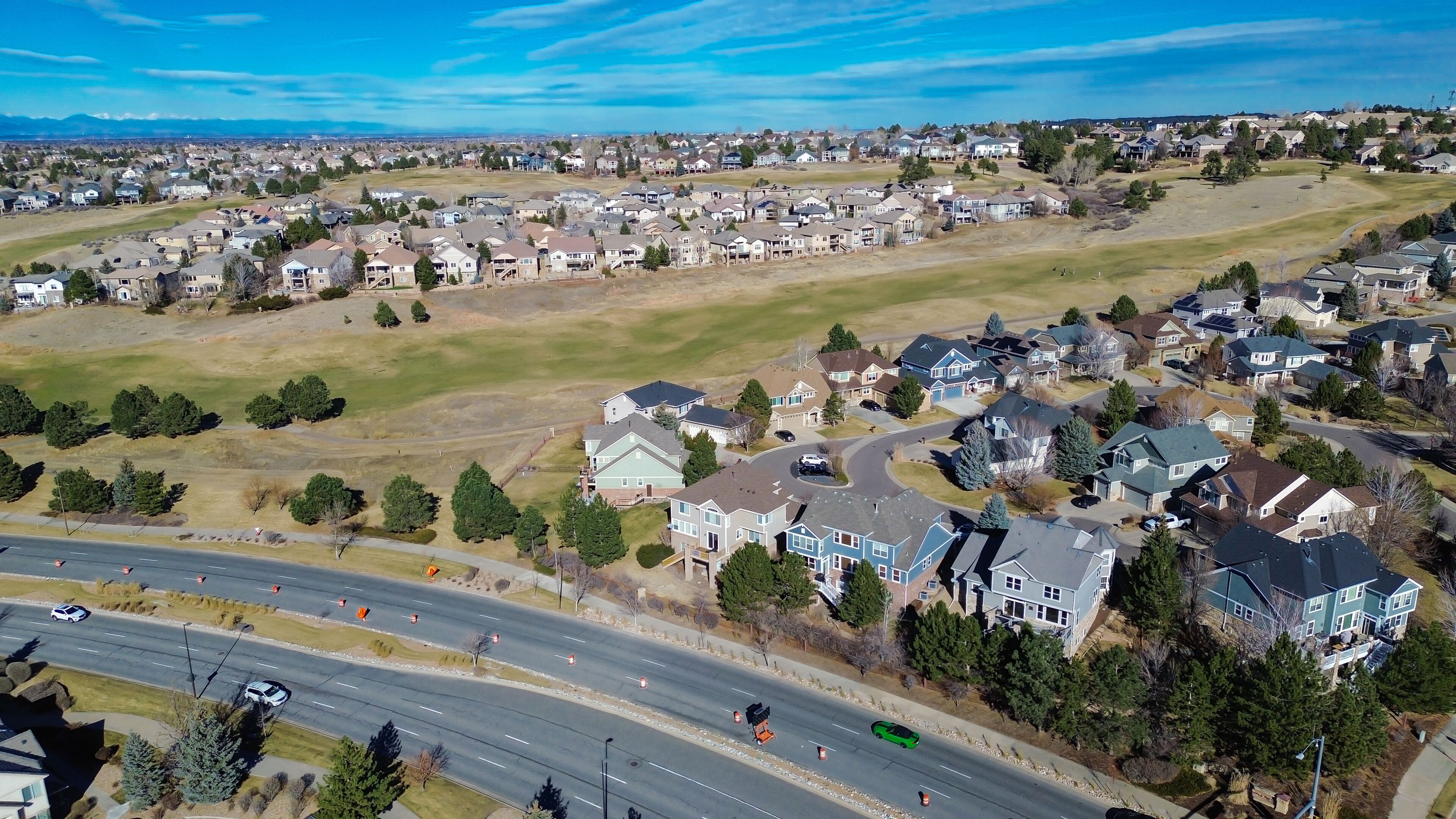Curving streets and dense homes east of E Arapahoe Rd extend toward rolling hills near E 470. Varied roof palettes, tree clusters, muted grass tones create layered suburban textures in Aurora, CO