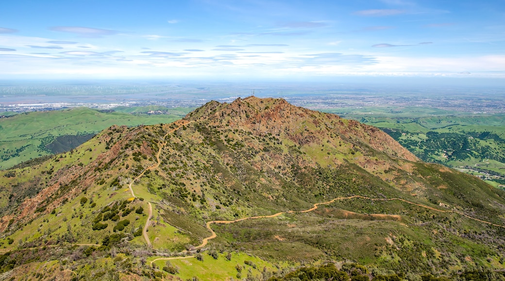 A mountain with a winding path and a city in the distance.