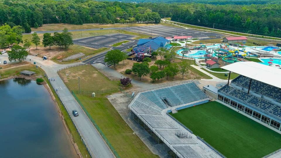 An aerial view of a sports complex with a stadium, parking lot, and water park.