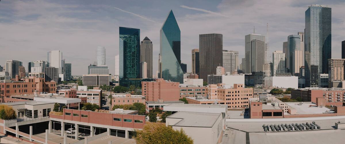 Wide panorama of downtown Dallas skyscrapers under blue sky