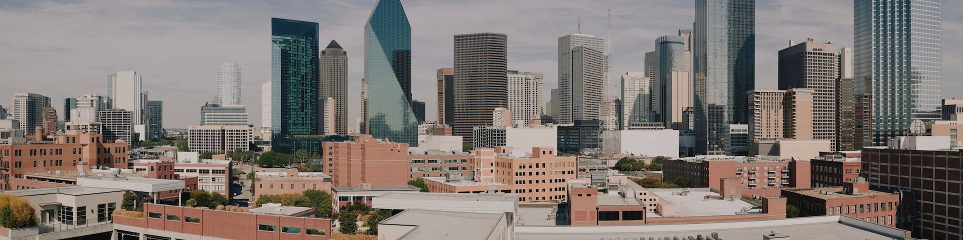 A cityscape with modern skyscrapers, a distinctive pyramid-shaped building, and a mix of older brick buildings.