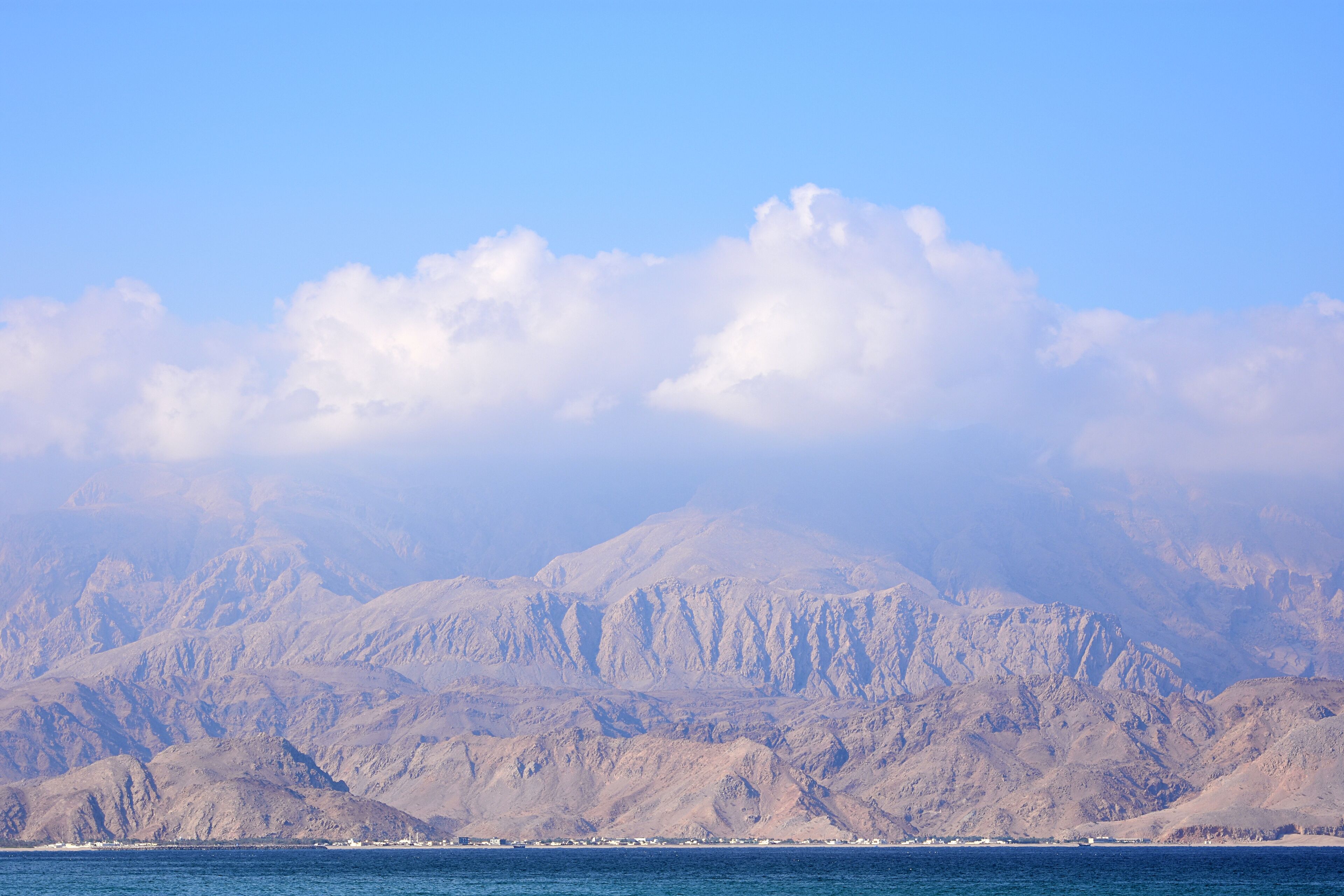 A mountainous landscape with a clear sky and a body of water in the foreground.