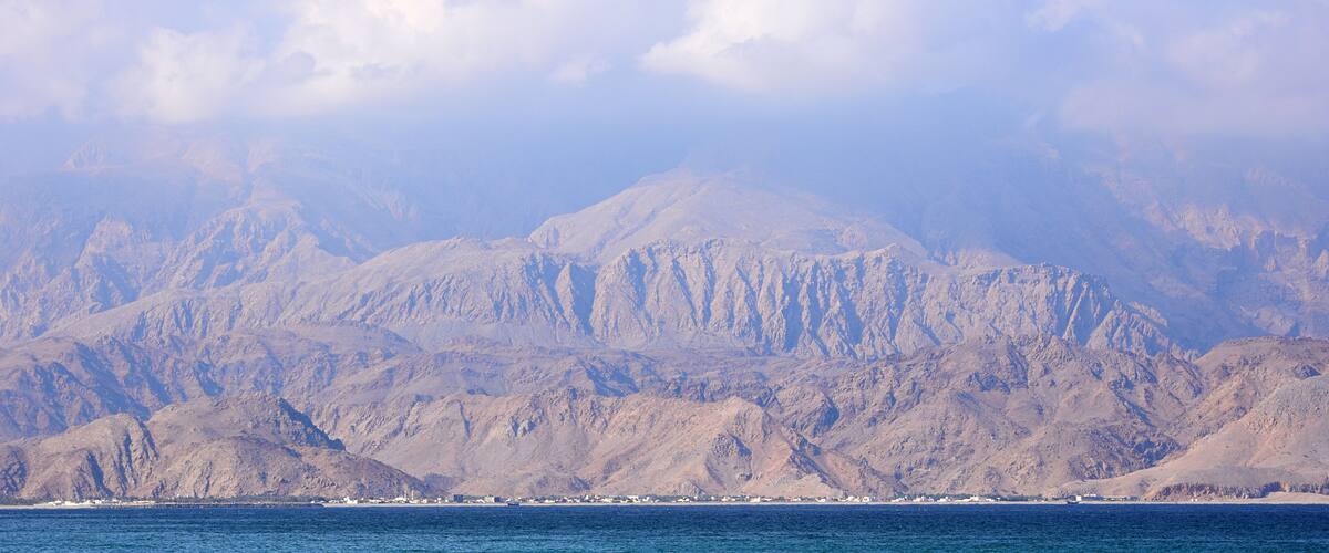 A mountainous landscape with a clear sky and a body of water in the foreground.