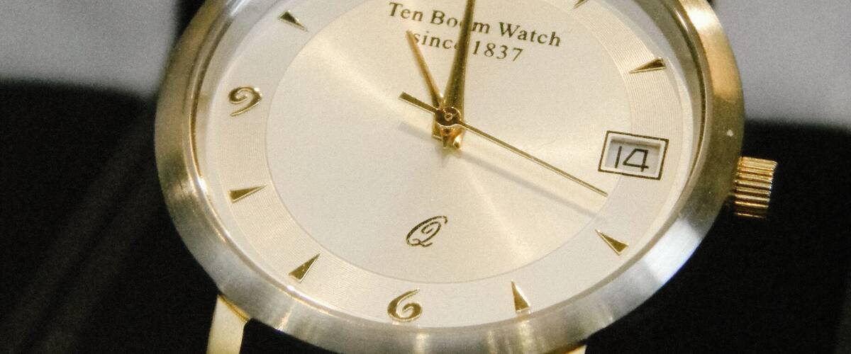 A Ten Boom Watch with a white face and gold hands.