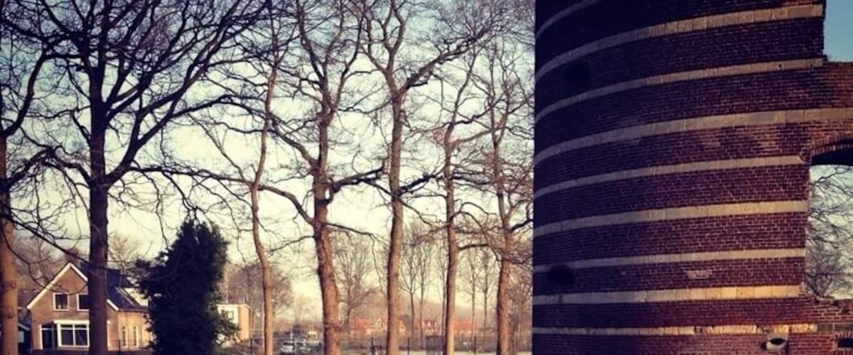 A river reflecting trees and a brick structure.