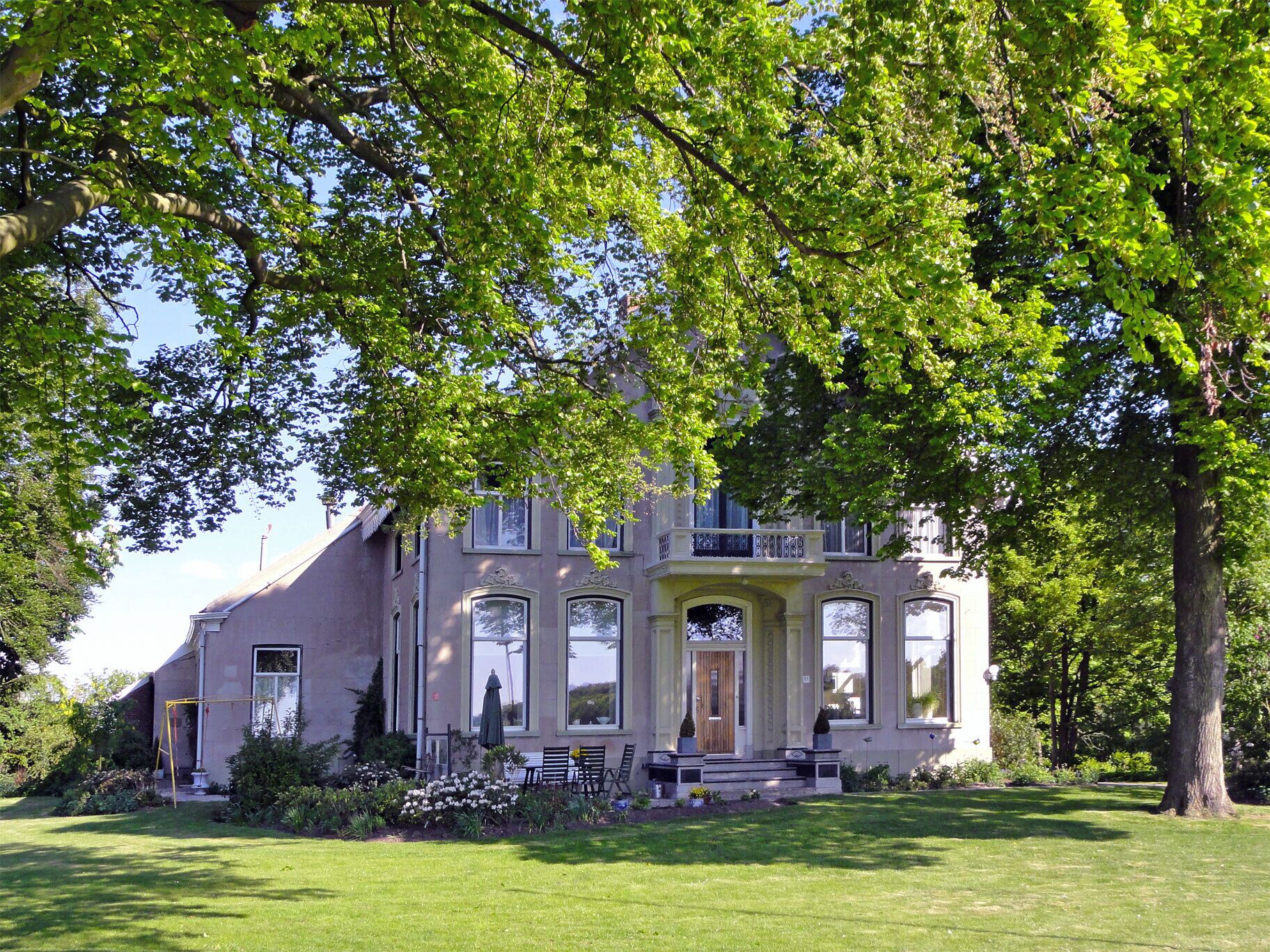 A large, historic house with a well-maintained lawn and a swing set.